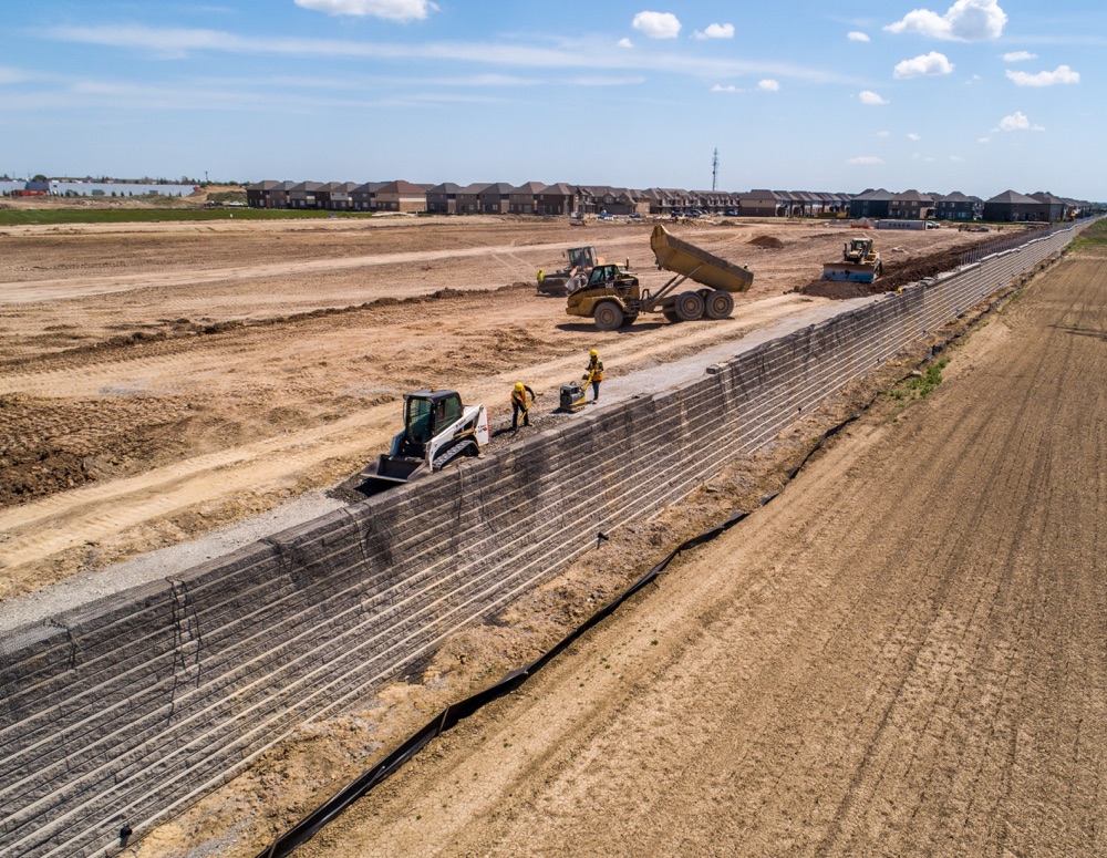 subdivision construction of retaining wall along farmer field