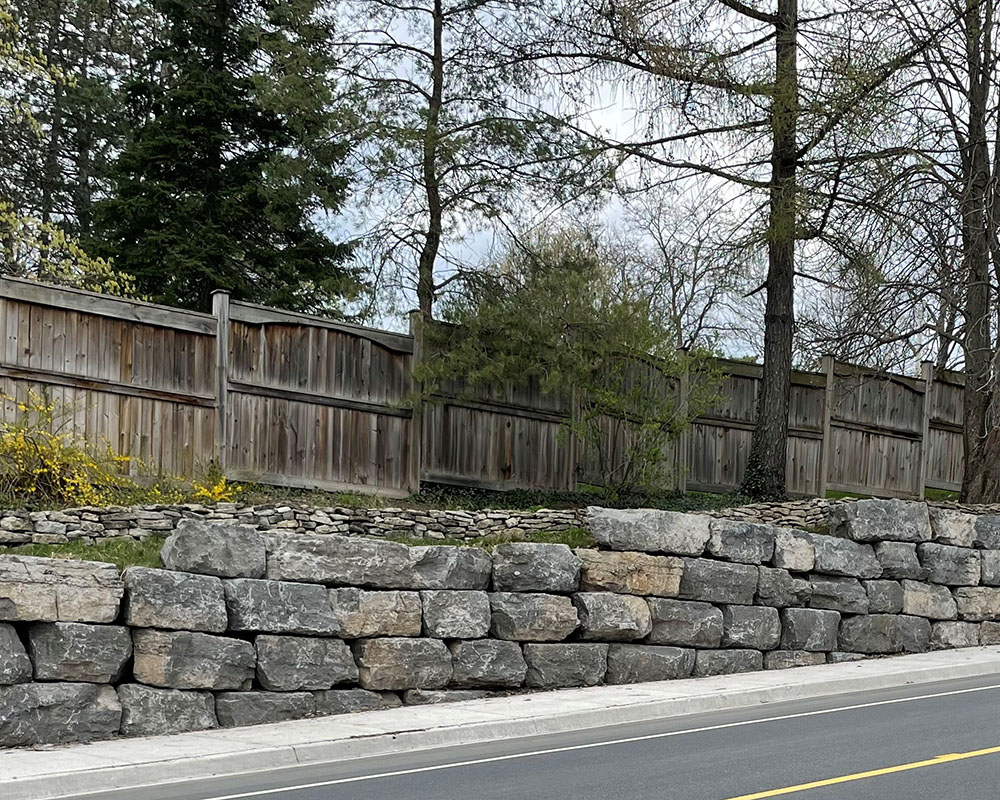 Retaining wall with large quarry stones and fence